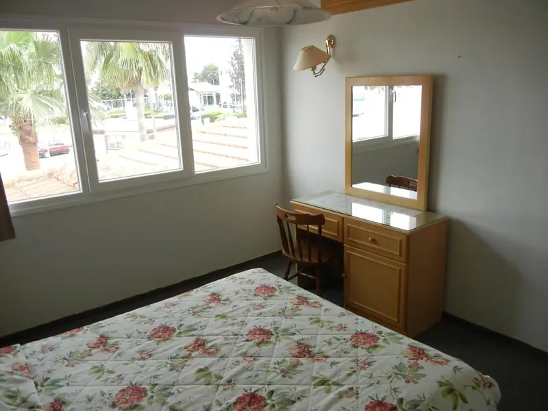 Une chambre lumineuse avec un lit recouvert d'une courtepointe florale et un coin coiffeuse.