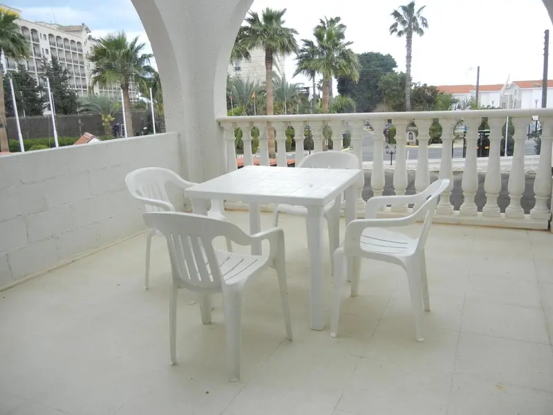 Terrasse avec mobilier blanc en plastique et vue sur la végétation.