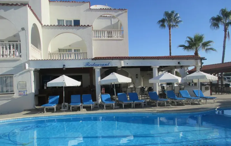 Terrasse de restaurant avec chaises longues bleues près d'une piscine.