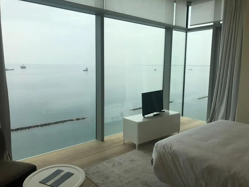Une chambre lumineuse avec vue sur la mer par de grandes baies vitrées.