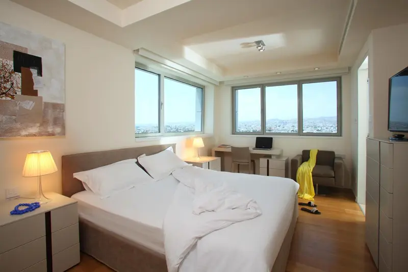 Une chambre lumineuse avec un grand lit et une vue sur la ville.