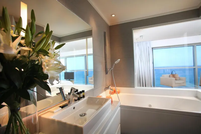 Une salle de bain lumineuse avec baignoire et vue sur la mer.
