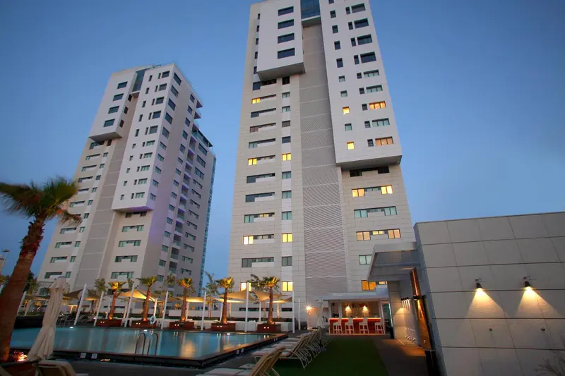 Immeubles modernes blancs avec des balcons et une piscine en contrebas.
