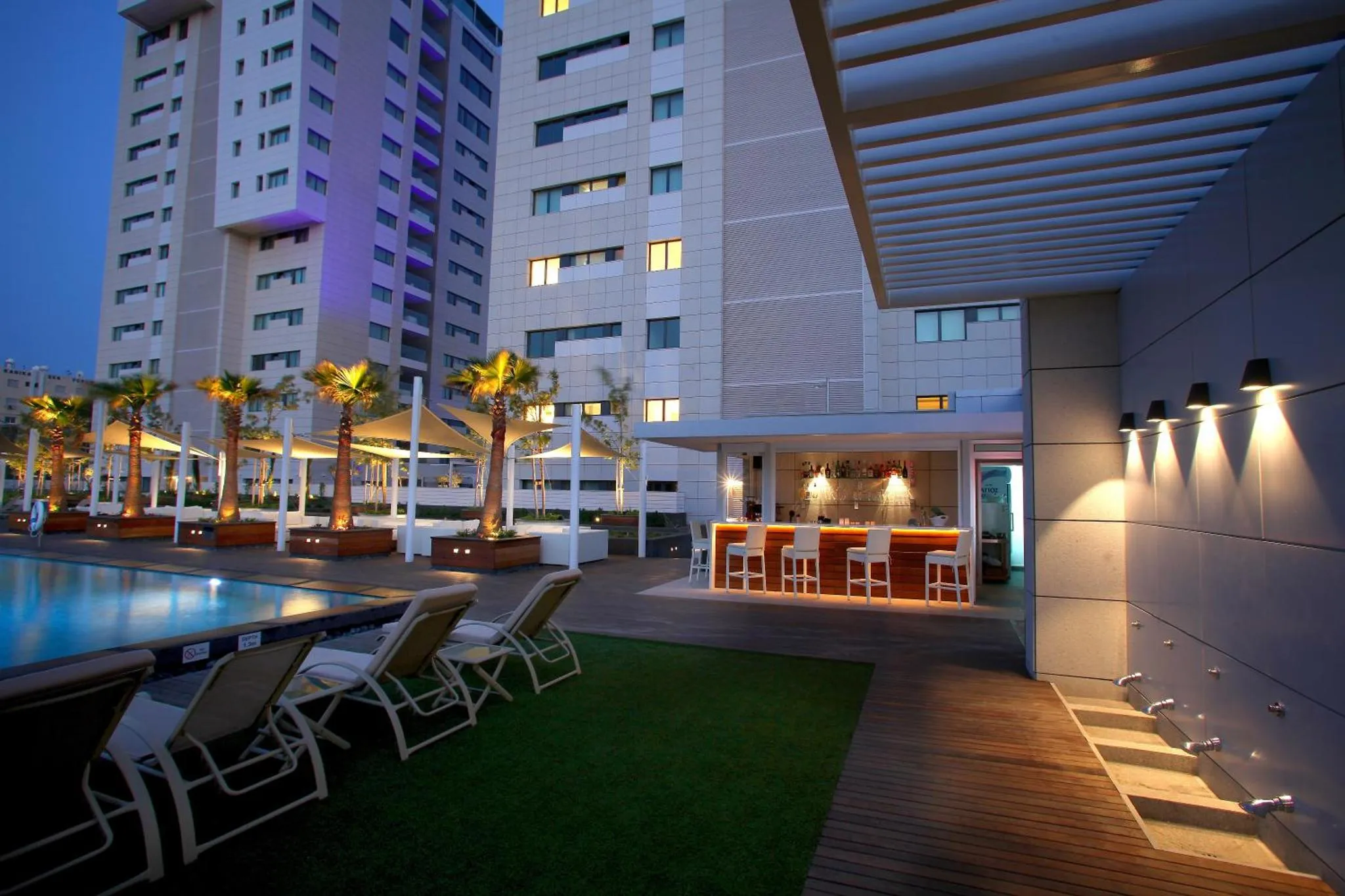Terrasse avec bar et piscine au bord d'un bâtiment moderne.