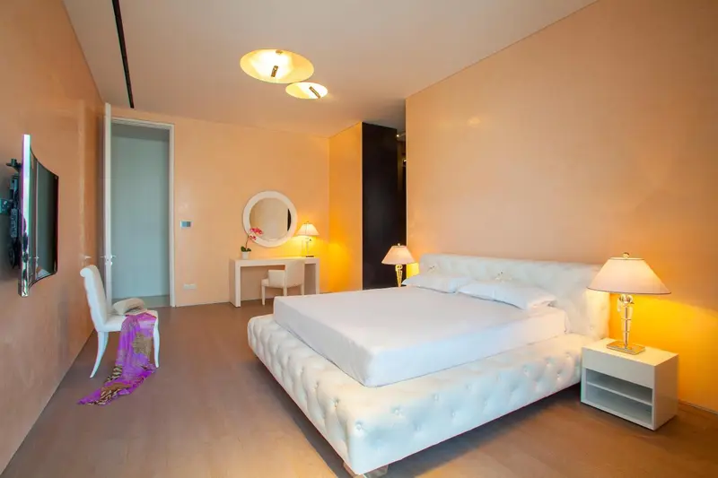 Une chambre lumineuse avec un grand lit blanc et une coiffeuse.