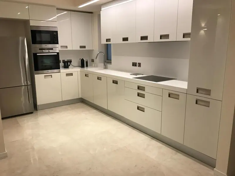 Cuisine moderne avec des meubles blancs et un plan de travail clair.