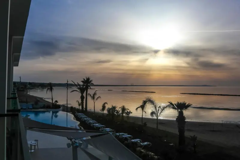 Vue d'une plage au coucher du soleil avec des palmiers et des transats.