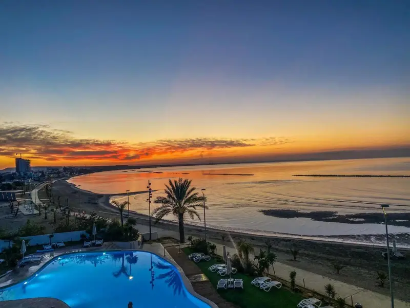 Vue aérienne d'une plage au coucher du soleil avec une piscine à l'avant-plan.