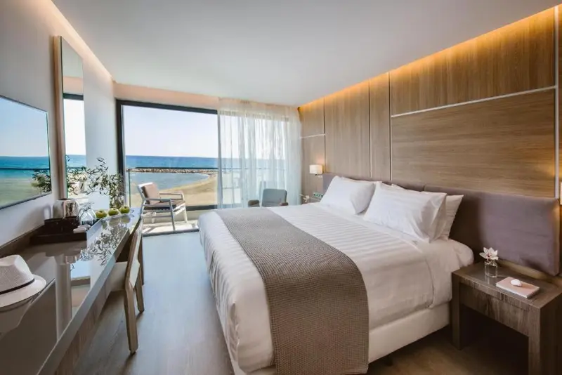 Chambre lumineuse avec un grand lit et vue sur la mer.