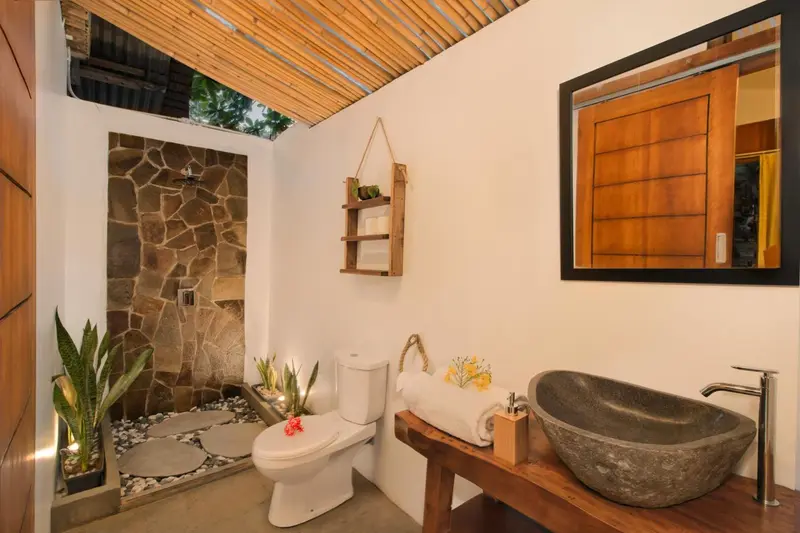 Une salle de bain avec douche à l'italienne et lavabo en pierre.