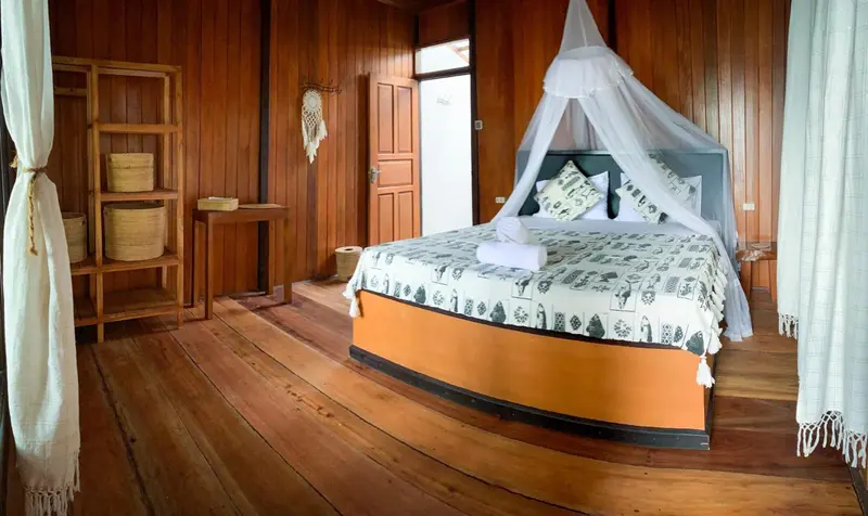 Une chambre lumineuse avec un lit recouvert d'une moustiquaire et des paniers en osier.