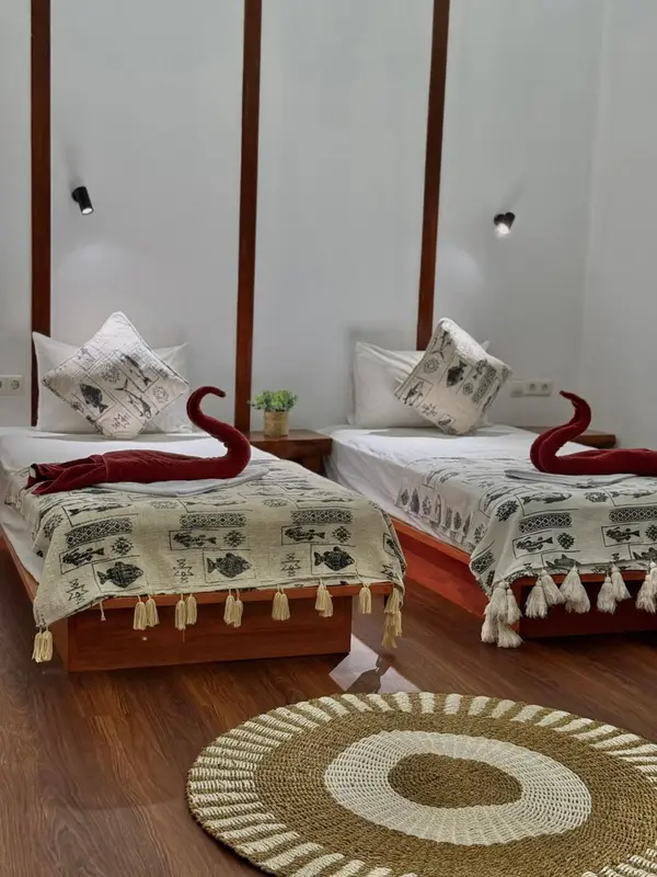 Deux lits simples décorés de couvertures à motifs dans une chambre lumineuse.