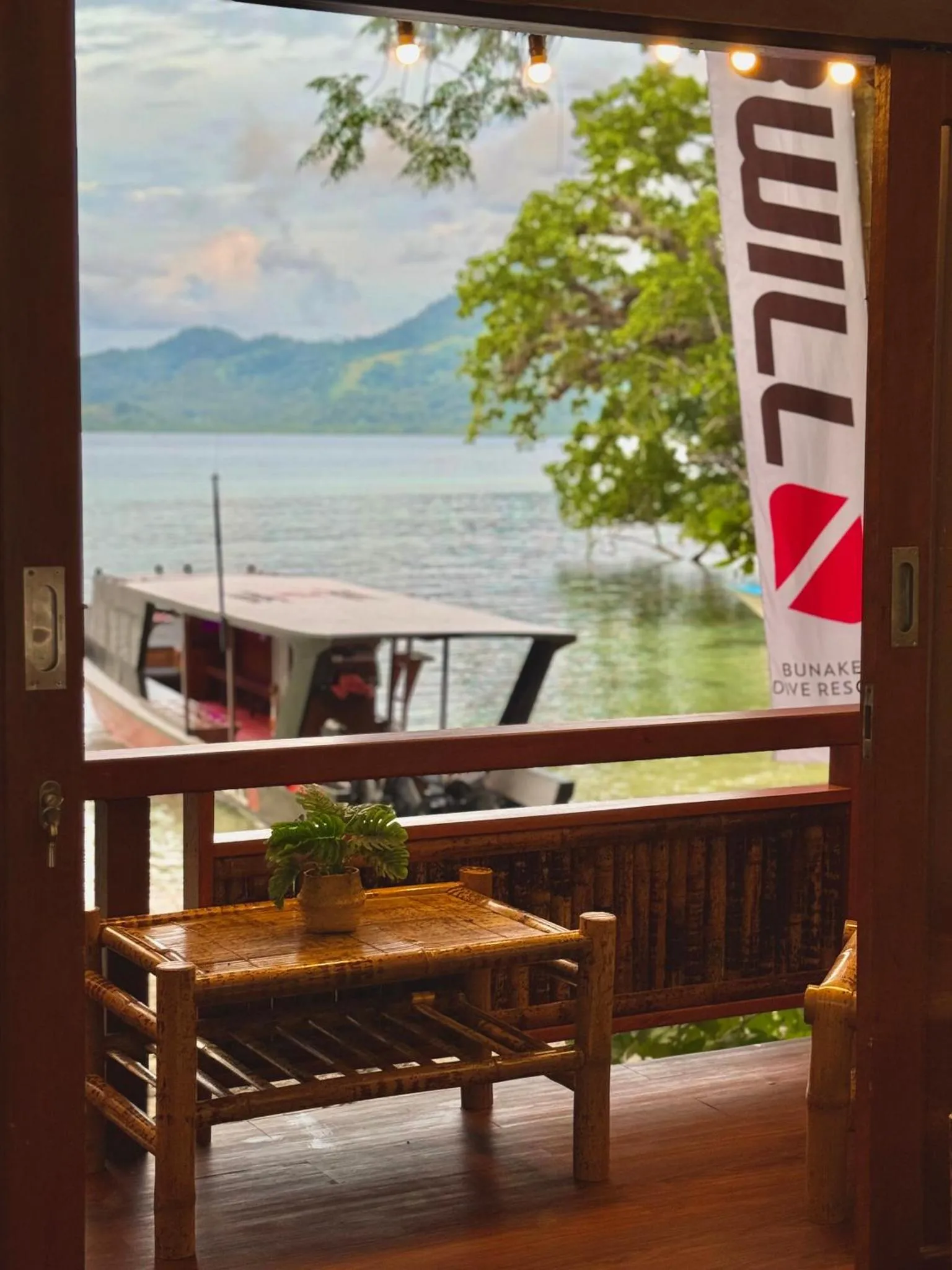 Vue sur la mer depuis une terrasse ombragée avec mobilier en rotin.