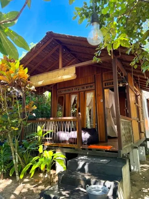 Petite maison en bois sur pilotis avec une terrasse et un lit à baldaquin.