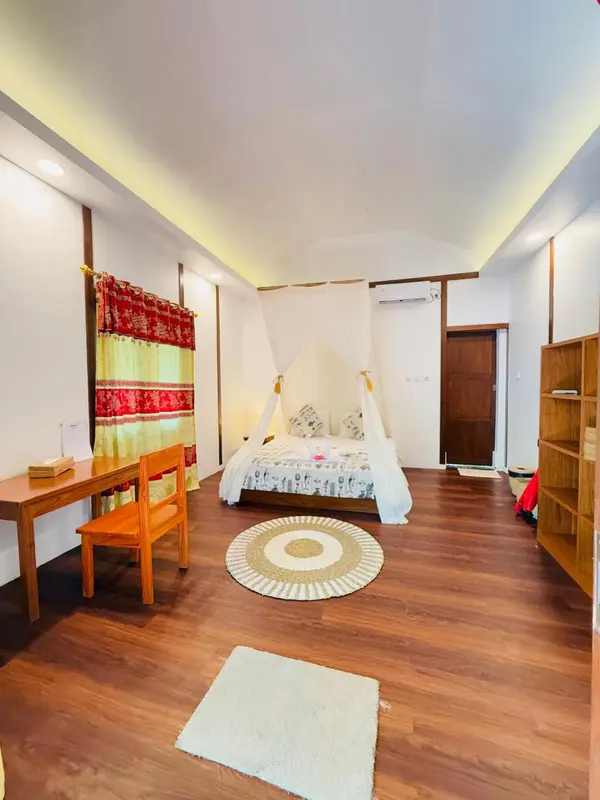 Une chambre lumineuse avec un lit à baldaquin et un bureau en bois.
