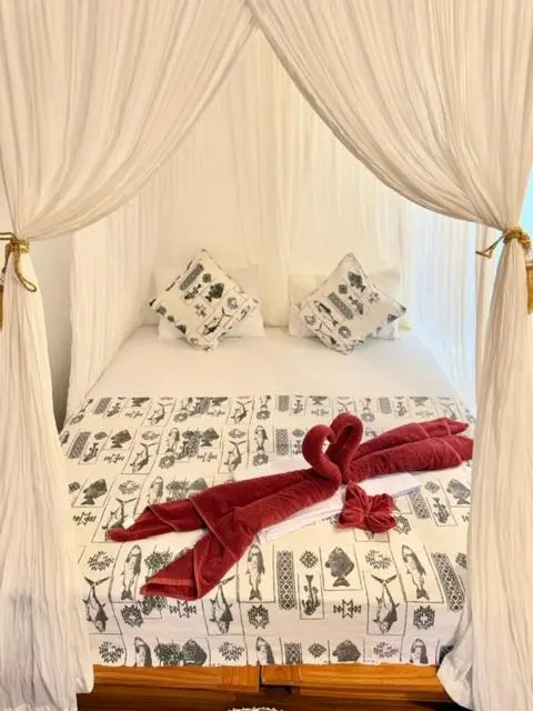Un lit recouvert de draps blancs et d'une courtepointe à motifs, décoré de serviettes en forme de cygnes.
