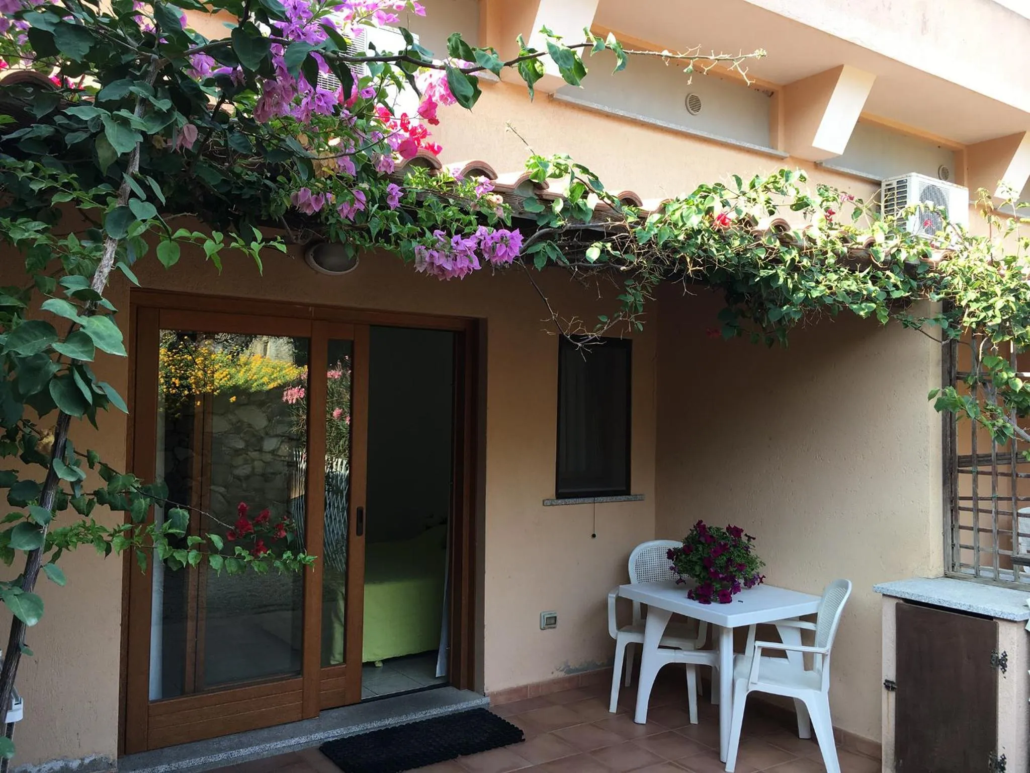 Une terrasse ombragée par des bougainvilliers donne sur une entrée et un coin repas.