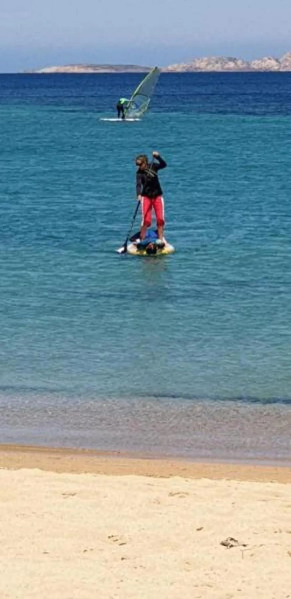 Deux personnes pratiquent des sports nautiques sur une eau turquoise.
