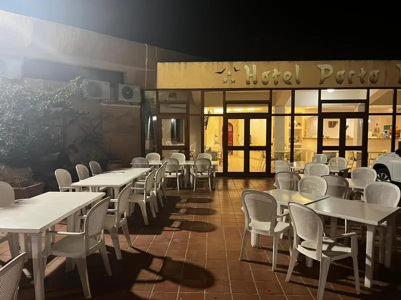 Terrasse d'hôtel avec tables et chaises en plastique sous un éclairage nocturne.