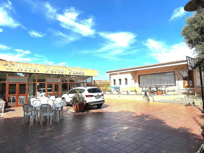 Façade d'un bâtiment bas avec une cour pavée et des tables de jardin.