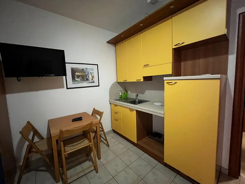 Une kitchenette jaune et une petite table à manger se trouvent dans une pièce lumineuse.