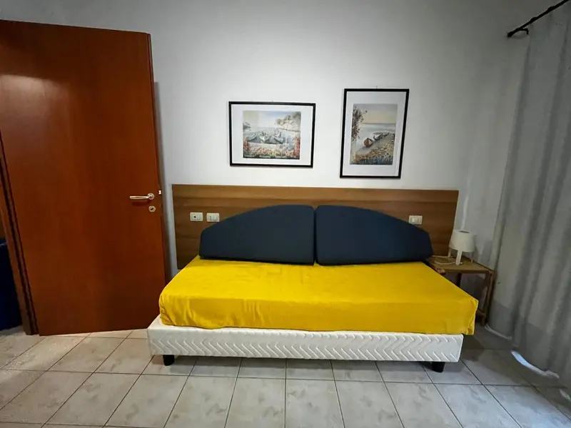 Une chambre lumineuse avec un grand lit recouvert d'une couverture jaune.