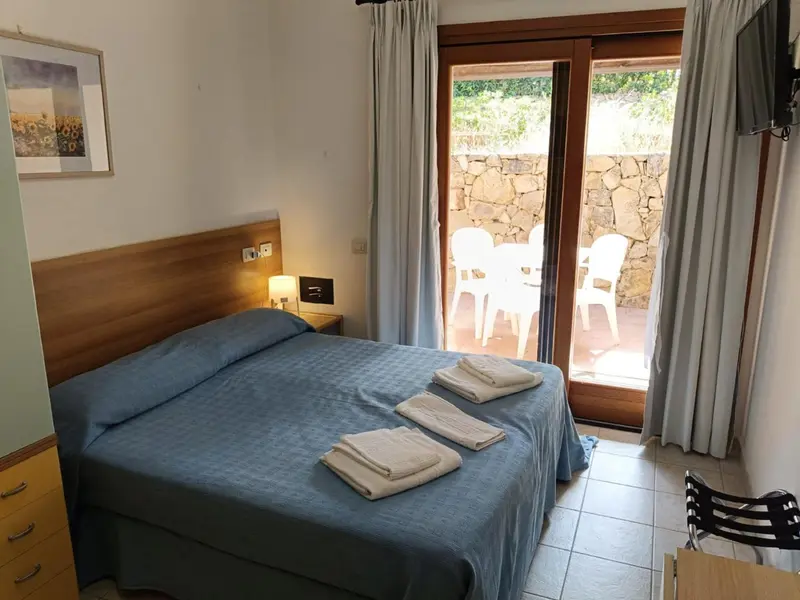Une chambre lumineuse avec un lit fait et un accès à une terrasse.