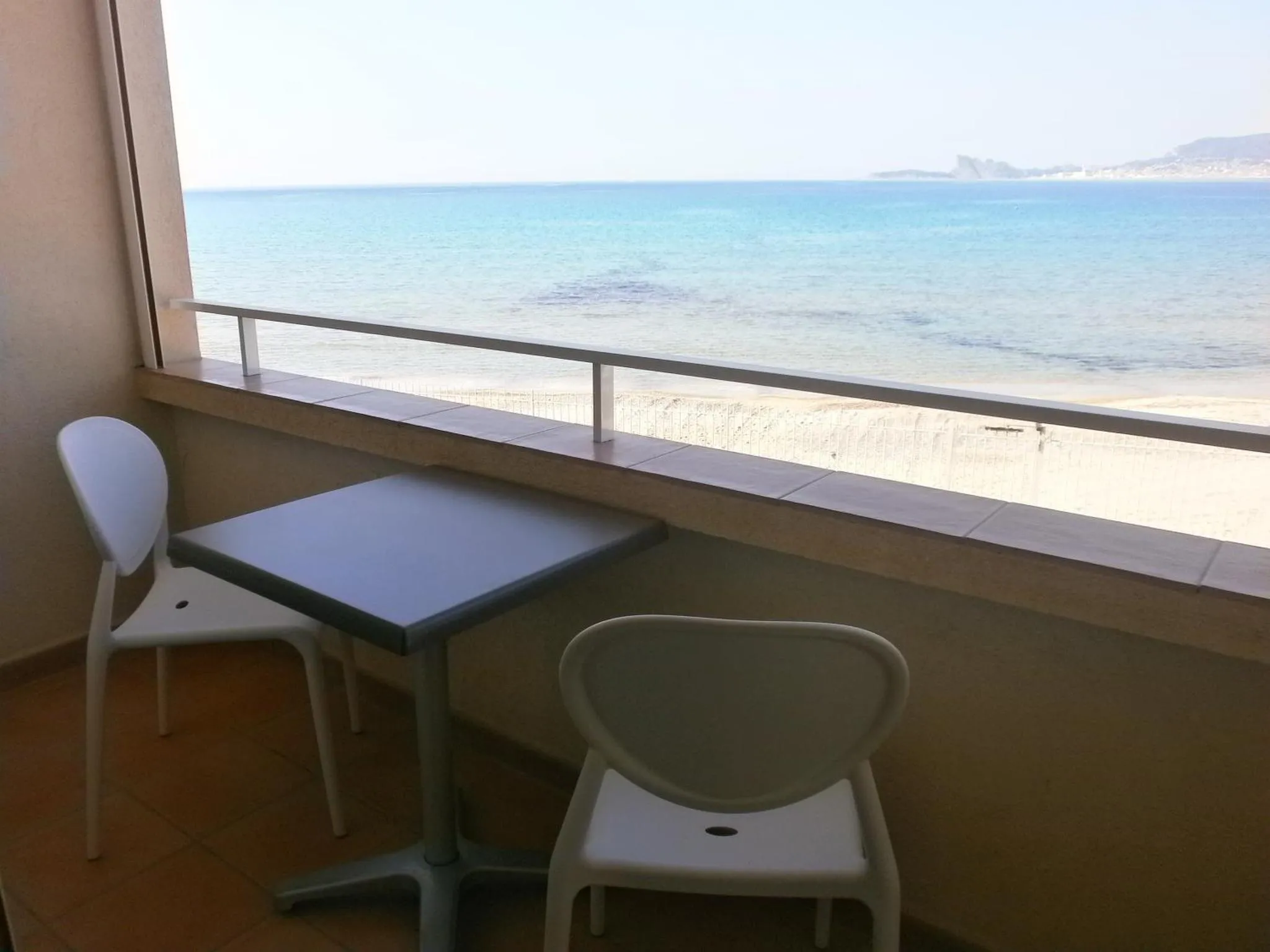 Une terrasse avec une table et des chaises offre une vue sur la mer et la plage.