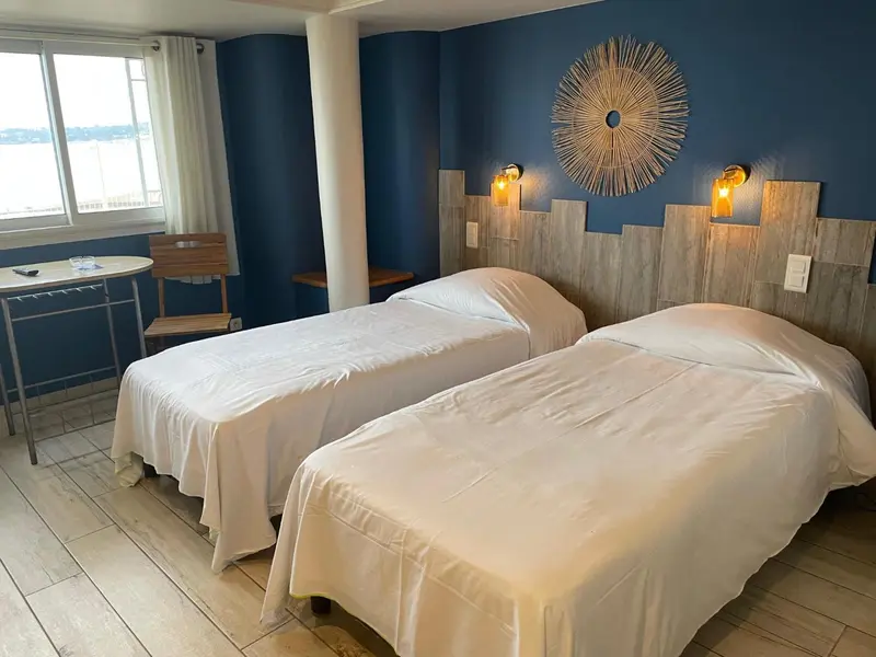 Une chambre lumineuse avec deux lits simples et une décoration murale.