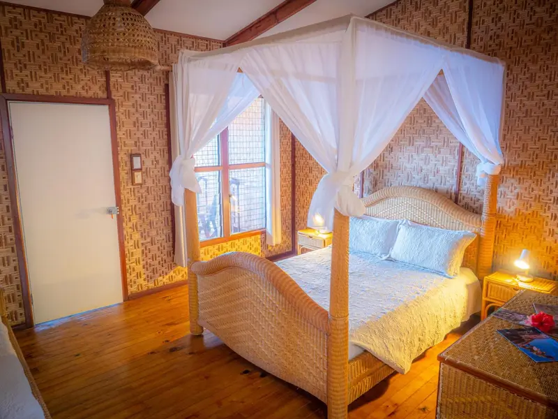 Une chambre lumineuse avec un lit à baldaquin et un sol en bois.