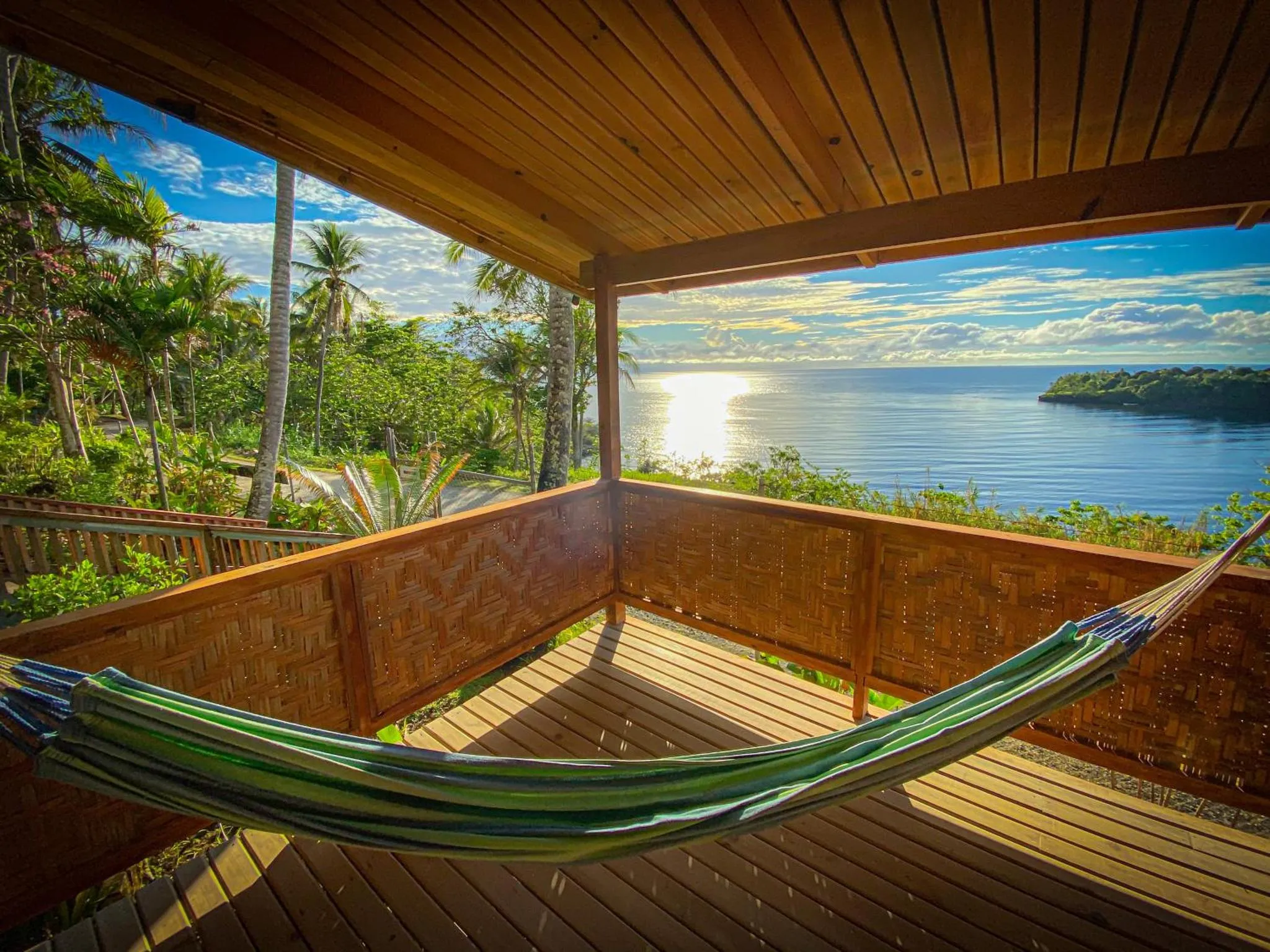 Une vue sur la mer depuis une terrasse en bois avec un hamac.