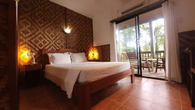 Une chambre lumineuse avec un grand lit et une terrasse en bois.