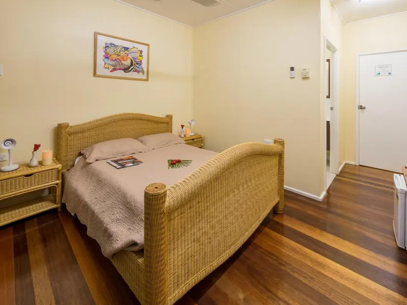 Une chambre lumineuse avec un grand lit en rotin et une décoration sobre.