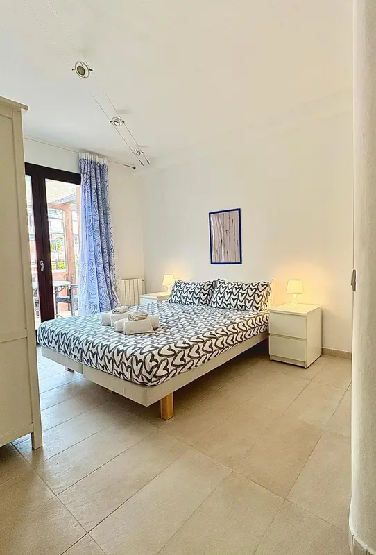 Une chambre lumineuse avec un grand lit recouvert d'une couette à motifs.