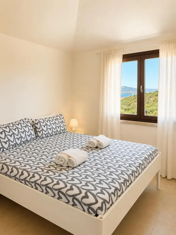 Une chambre lumineuse avec un grand lit décoré de coussins et une vue sur la mer.