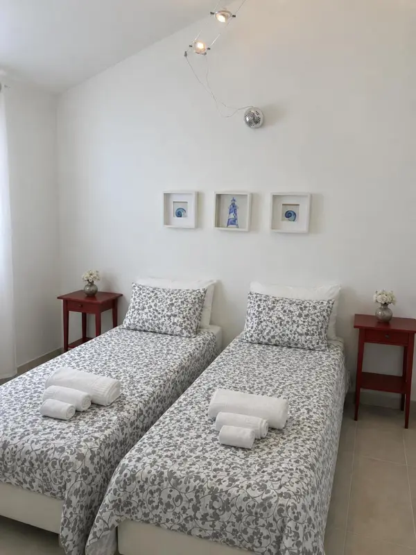 Une chambre lumineuse avec deux lits simples et des tables de chevet rouges.
