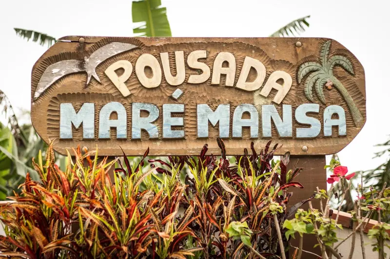 Enseigne en bois sculpté avec le nom de l'établissement et des motifs tropicaux.