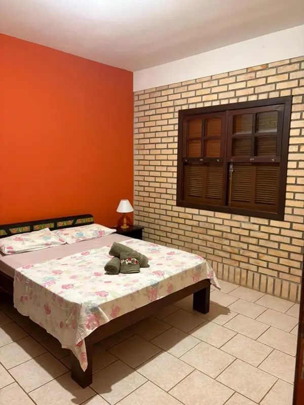 Une chambre avec un lit recouvert d'une courtepointe fleurie et un mur en briques.