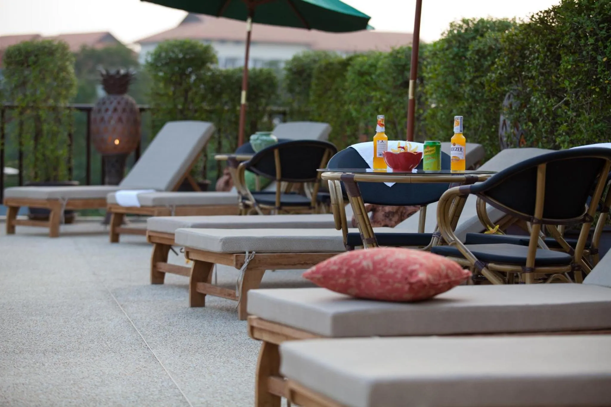 Transats et tables basses avec boissons sur une terrasse ensoleillée.