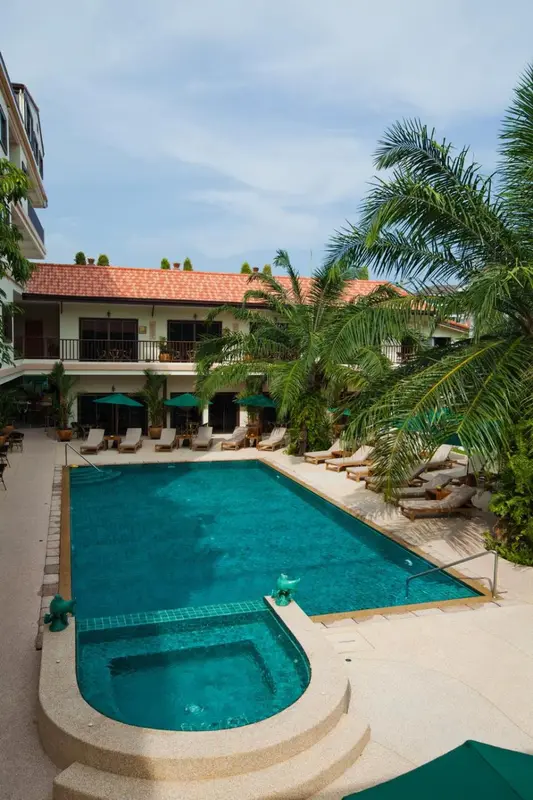 Une piscine turquoise bordée de transats dans un jardin tropical.