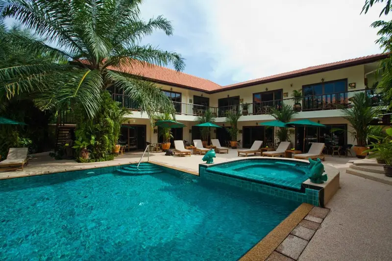 Une piscine turquoise bordée de chaises longues dans un jardin tropical.