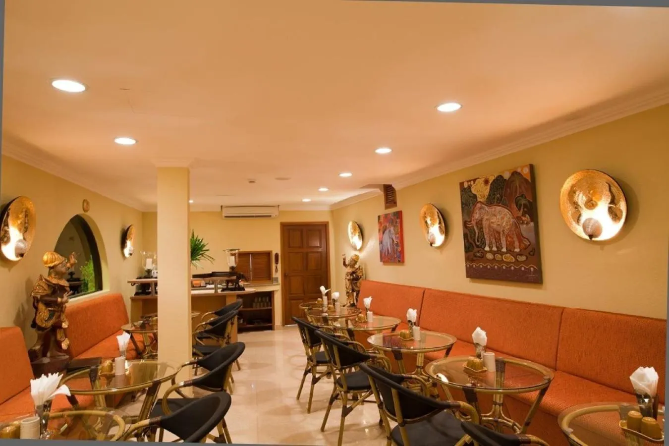 Une salle de restaurant avec des tables rondes et des banquettes orange.