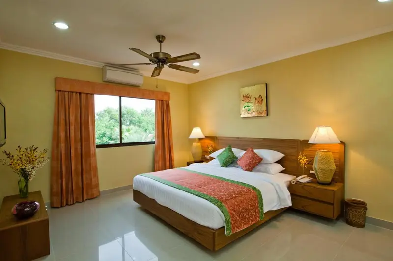 Une chambre lumineuse avec un grand lit et une fenêtre donnant sur la végétation.