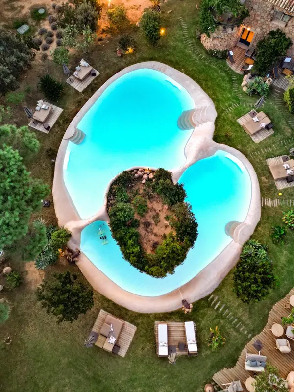 Vue aérienne d'une piscine en forme de cœur entourée d'une pelouse verdoyante et de transats.