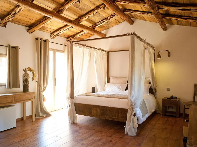Une chambre lumineuse avec un lit à baldaquin et un parquet en bois.