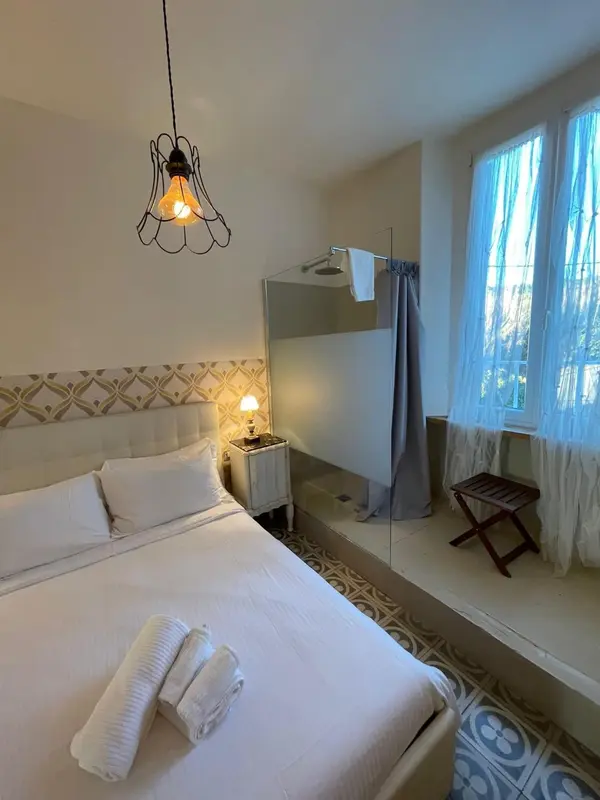 Une chambre lumineuse avec un lit fait et une salle de bain attenante.
