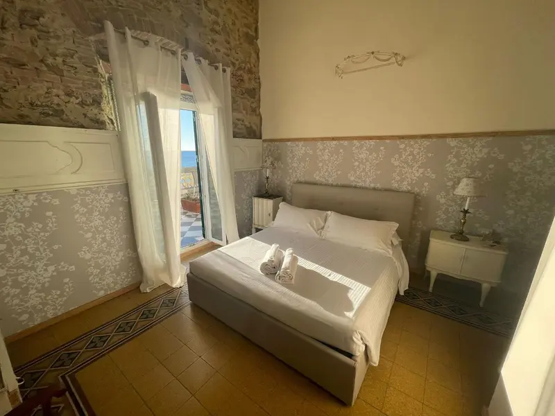 Chambre lumineuse avec un lit double et une vue sur la mer.