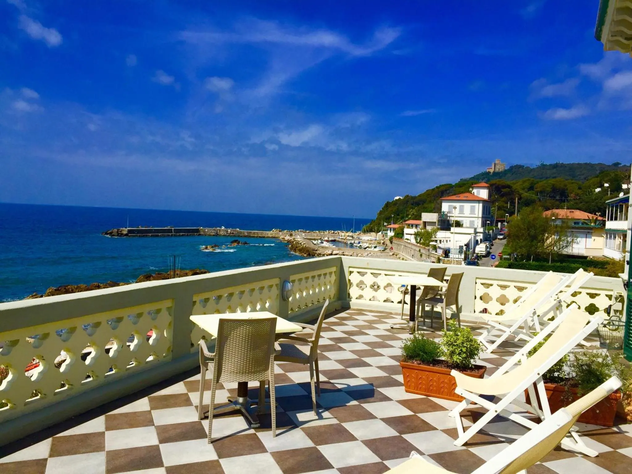 Terrasse carree avec mobilier de jardin et vue sur la mer.