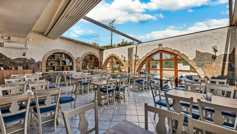 Une salle de restaurant à l'architecture en pierre avec des tables et des chaises.