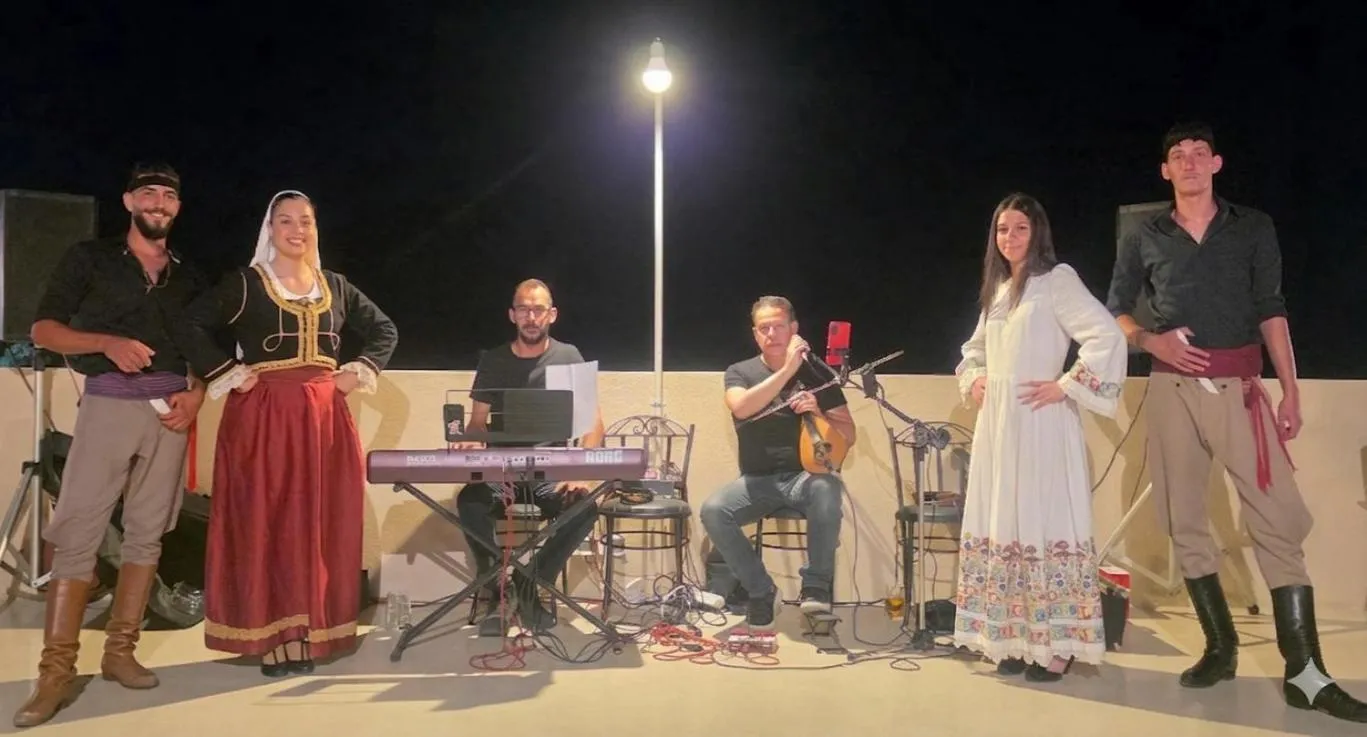 Un groupe de personnes joue de la musique et danse sur une terrasse éclairée.